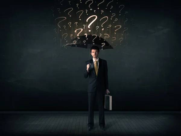 Businessman with umbrella and a lot of drawn question marks — Stock Photo, Image