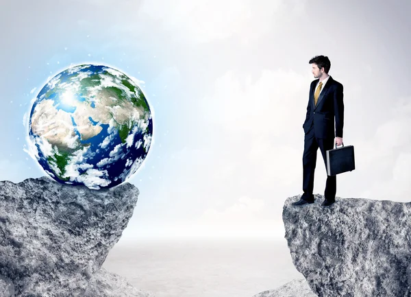 Businessman on rock mountain with a globe — Stock Photo, Image