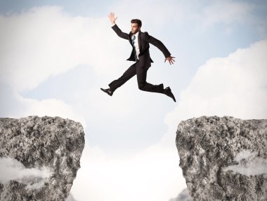 Komik iş adamı kayaların üzerinden atlıyor.