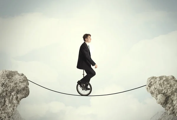 Brave business man riding an mono cycle between cliffs — Stock Photo, Image