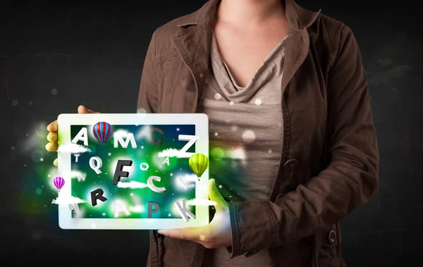 Young person showing tablet with abstract letters and sky — Stock Photo, Image