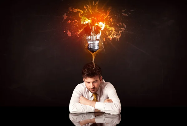 Businessman sitting under a blowing idea bulb — Stock Photo, Image