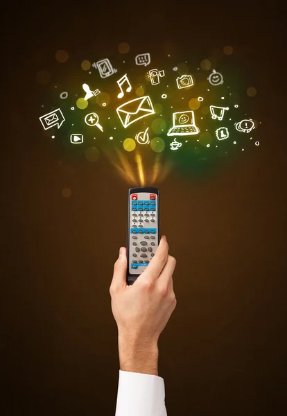 Hand with remote control and social media icons — Stock Photo, Image