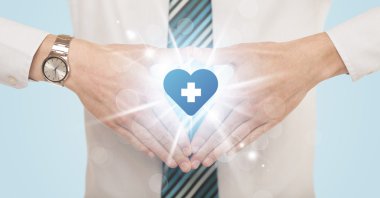 Eller mavi haçlı bir kalp yaratıyor.