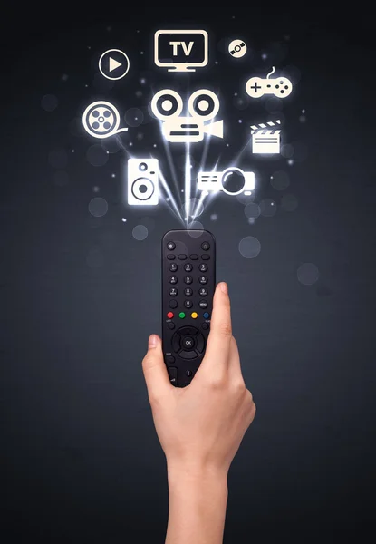 Hand with remote control and media icons — Stock Photo, Image