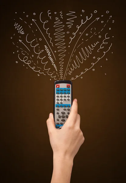 Hand with remote control and curly lines — Stock Photo, Image