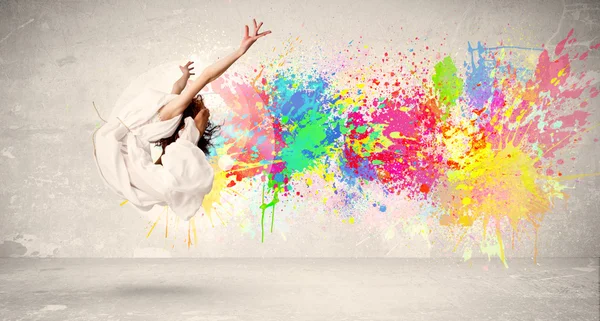 Happy teenager jumping with colorful ink splatter on urban backg — Stock Photo, Image