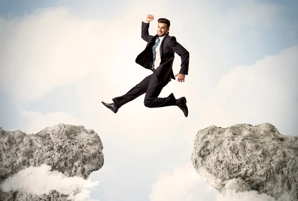 Happy business man jumping over a cliff — Stock Photo, Image