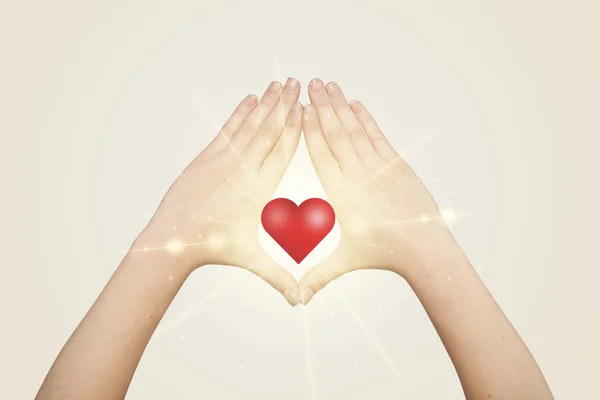 Mains créant une forme avec un cœur brillant — Photo