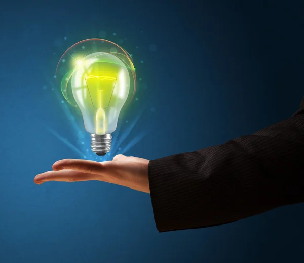 Glowing lightbulb in the hand of a businessman — Stock Photo, Image