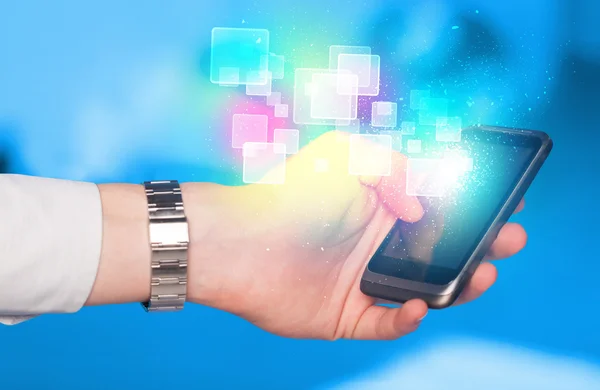 Hand holding smart phone with abstract glowing squares — Stock Photo, Image