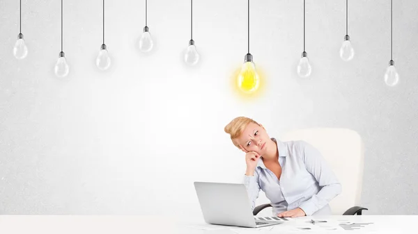 Geschäftsfrau sitzt mit Idee Glühbirnen am Tisch — Stockfoto