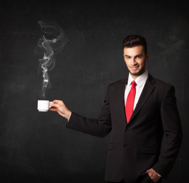 Beyaz buharlı bir bardak tutan bir iş adamı.