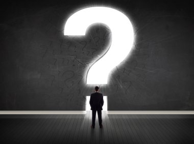 Parlak bir soru işaretiyle duvara bakan bir iş adamı 