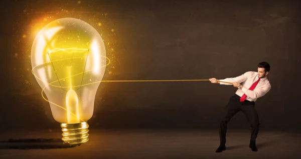 Uomo d'affari tirando una grande lampadina luminosa brillante — Foto Stock