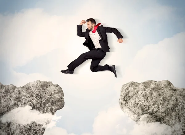 Happy business man jumping over a cliff — Stock Photo, Image