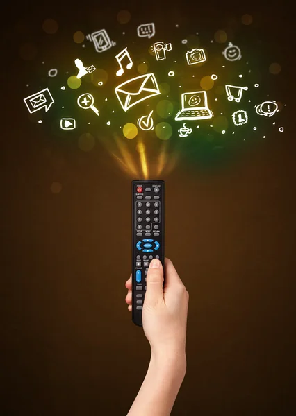 Hand with remote control and social media icons — Stock Photo, Image