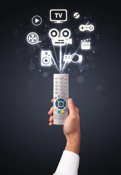 Hand with remote control and media icons — Stock Photo, Image