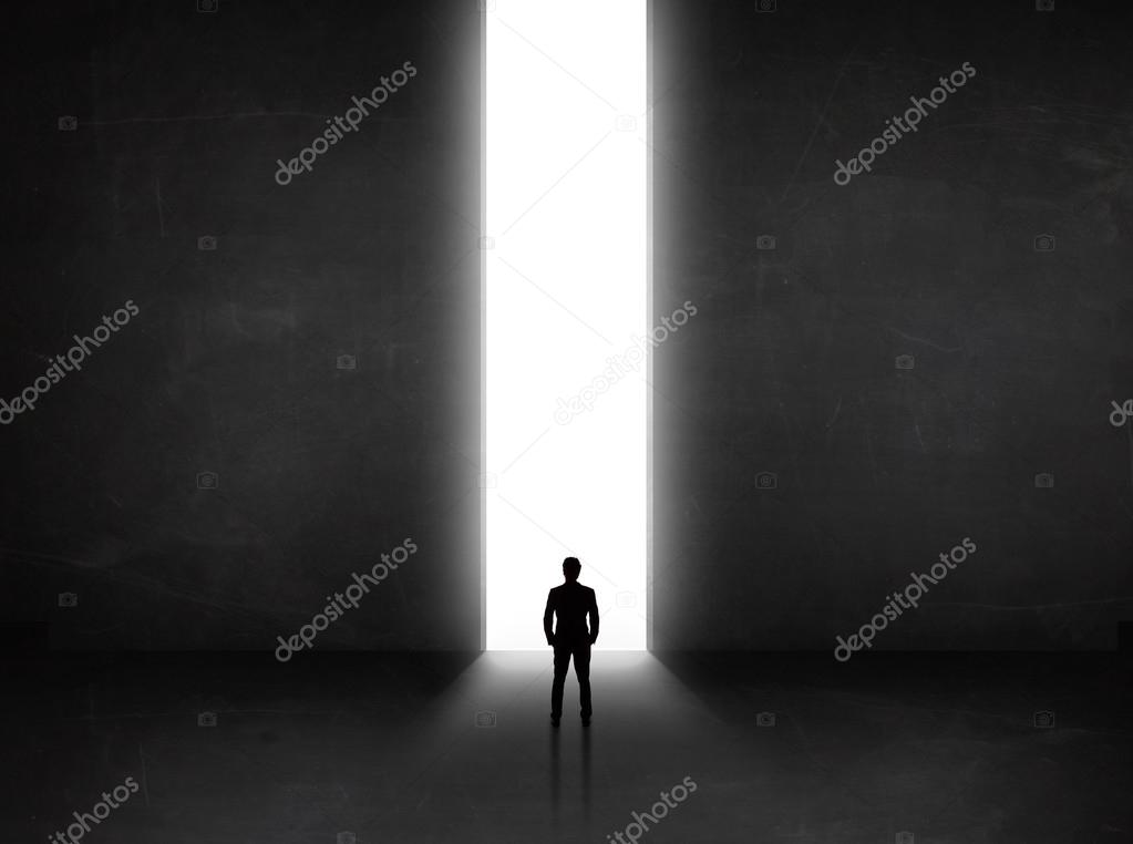 Business person looking at wall with light tunnel opening 