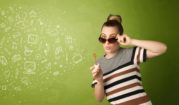 Cute girl blowing hand drawn media icons and symbols — Stock Photo, Image