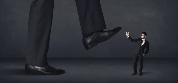 Giant person stepping on a little businessman concept — Stock Photo, Image