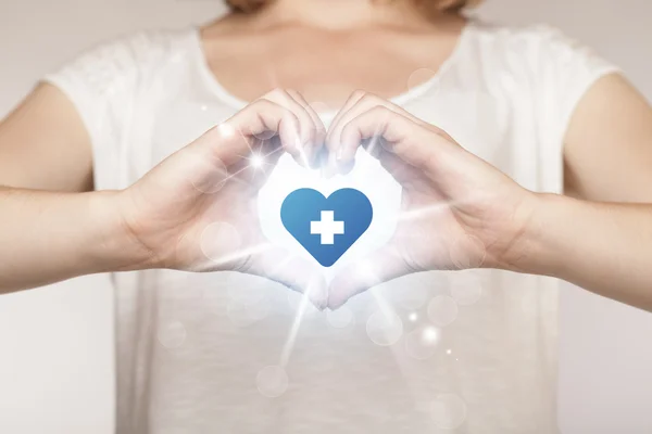 Manos creando una forma con corazón cruz azul — Foto de Stock