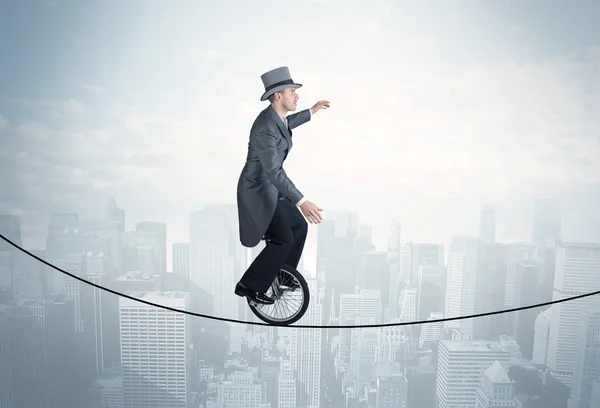 Een dappere man op een monocycle op een touw boven het stadsgezicht. — Stockfoto