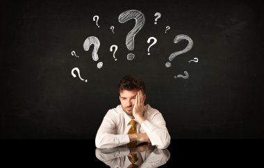 Soru işaretleri altında oturan işadamı