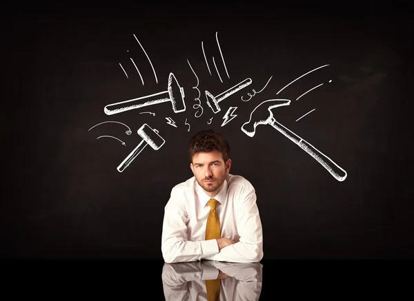 Depressed businessman sitting under hammer marks — Stock Photo, Image