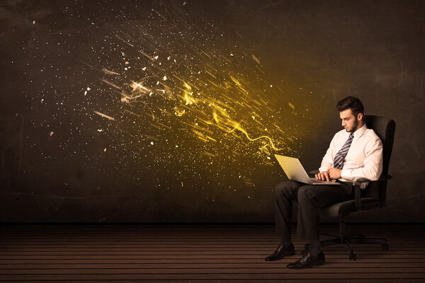 Businessman with laptop and energy explosion on background