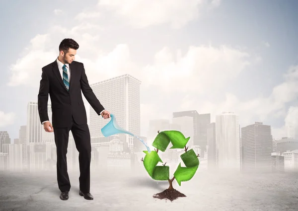 Geschäftsmann wässert grünen Recycling-Schilderbaum vor Stadthintergrund — Stockfoto