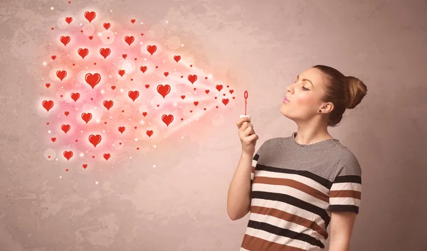 Pretty young girl blowing red heart symbols — Stock Photo, Image