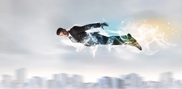 Hero superman flying above city with smoke left behind — Stock Photo, Image