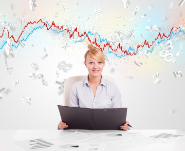 Borsa grafiğiyle masada oturan iş kadını. 