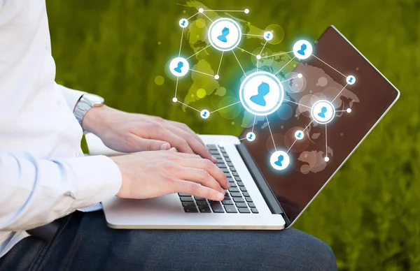 Close up of hand with laptop and social media icons — Stock Photo, Image