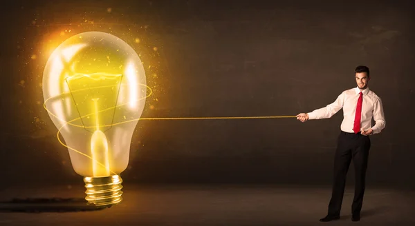 大きな明るい白熱電球を引っ張るビジネス男性 — ストック写真