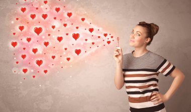 Güzel genç kız kırmızı kalp sembolleri üflüyor. 