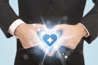 Eller mavi haçlı bir kalp yaratıyor.