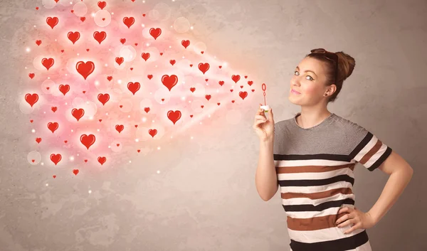 Pretty young girl blowing red heart symbols — Stock Photo, Image