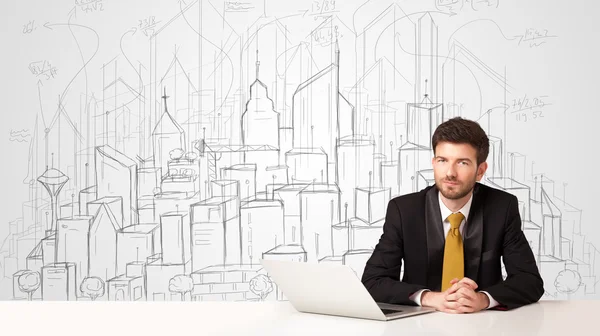 Businessman sitting at the white table with hand drawn buildings — Stock Photo, Image