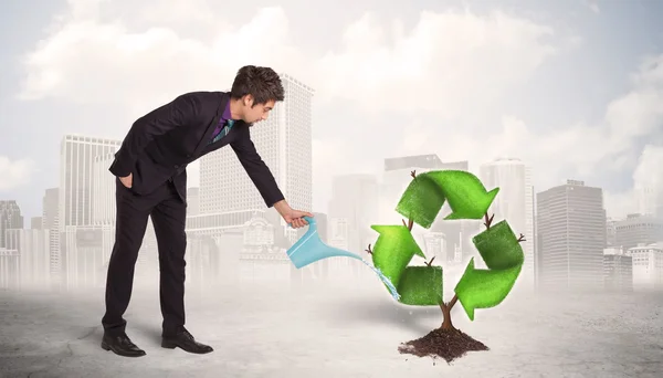 Business man watering green recycle sign tree on city background — Stock Photo, Image