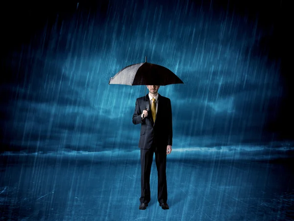 Hombre de negocios de pie bajo la lluvia con un paraguas —  Fotos de Stock