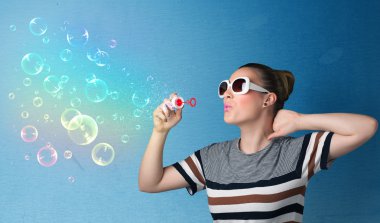 Mavi arka planda renkli kabarcıklar çıkaran güzel bayan.