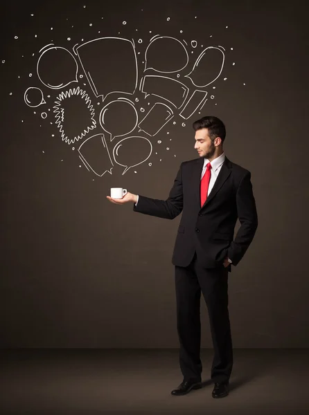 Businessman holding a white cup with speech bubbles — Stock Photo, Image