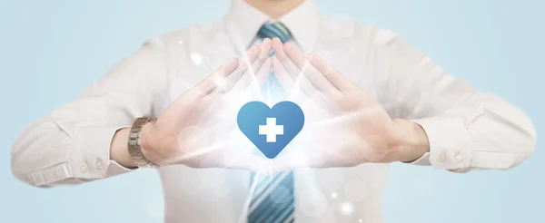 Manos creando una forma con corazón cruz azul — Foto de Stock