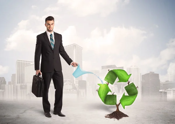 Business man watering green recycle sign tree on city background — Stock Photo, Image