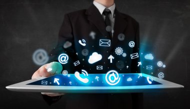 Mavi teknoloji simgeleri ve sembolleri olan bir tablet tutan kişi
