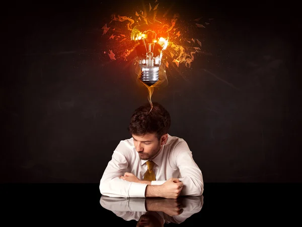 Businessman sitting under a blowing idea bulb — Stock Photo, Image