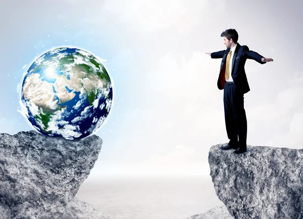 Businessman on rock mountain with a globe — Stock Photo, Image