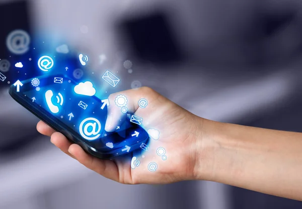 Business man holding smart phone with media icons — Stock Photo, Image